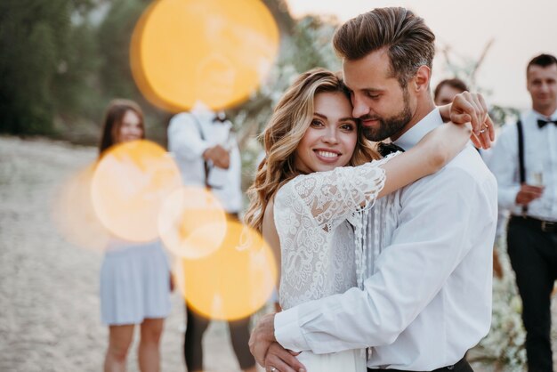 Belle mariée et le marié ayant leur mariage avec des invités sur une plage