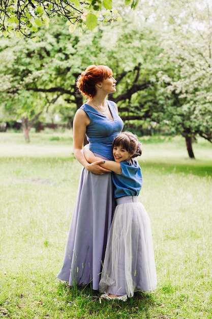 Belle mère et fille debout dans le jardin vert