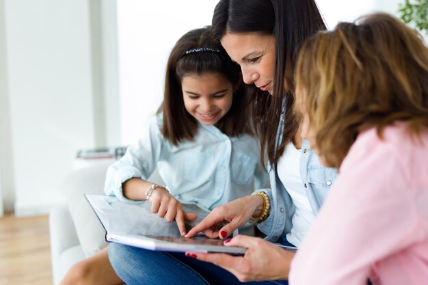 Belle mère avec ses filles qui lisent un livre à la maison.