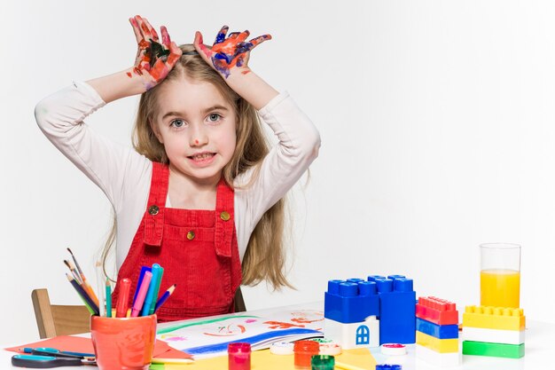 La belle petite fille aux mains dans la peinture