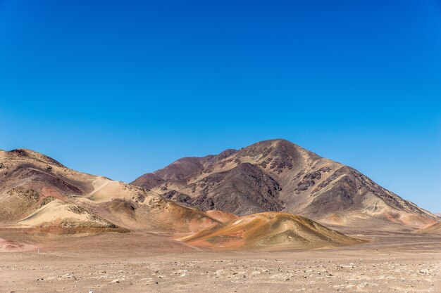 Belle photo d'un champ vide avec des montagnes au loin sous un ciel bleu clair