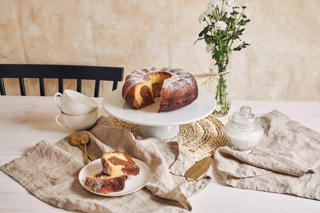 Belle photo d'un délicieux gâteau à l'anneau posé sur une assiette blanche et une fleur blanche à proximité