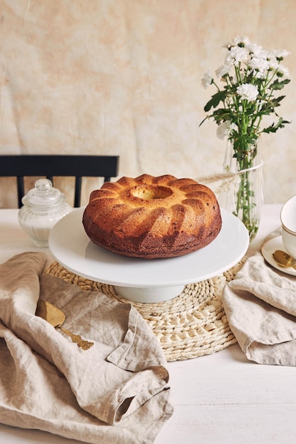 Belle photo d'un délicieux gâteau à l'anneau posé sur une assiette blanche et une fleur blanche à proximité