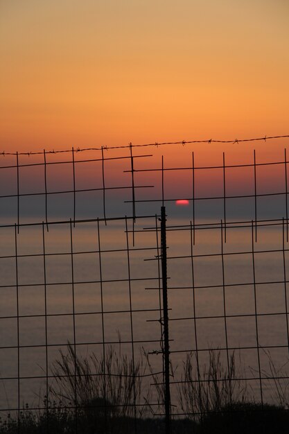 Belle photo du coucher de soleil sur l'océan derrière la clôture métallique en Crète