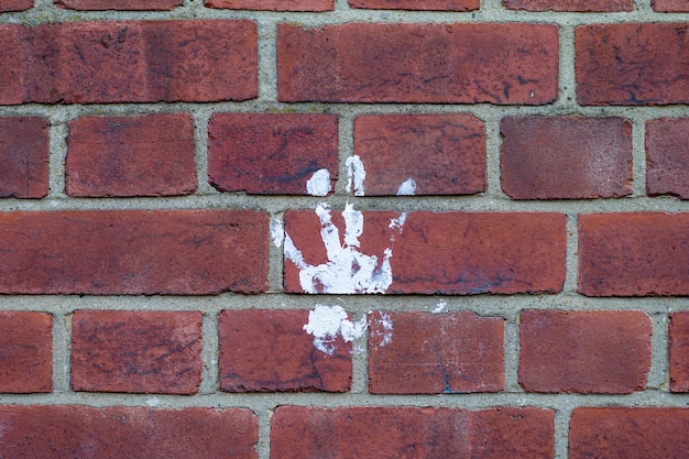 Belle photo d'une empreinte de main blanche sur un mur de briques