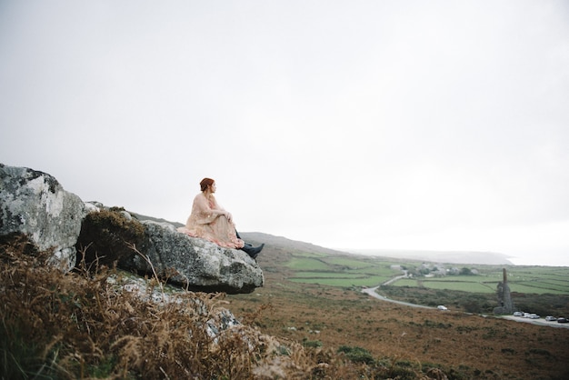 Belle photo d'une femme au gingembre avec une peau d'un blanc pur dans une jolie robe rose