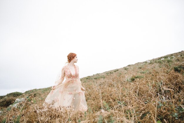 Belle photo d'une femme au gingembre avec une peau d'un blanc pur dans une robe rose clair