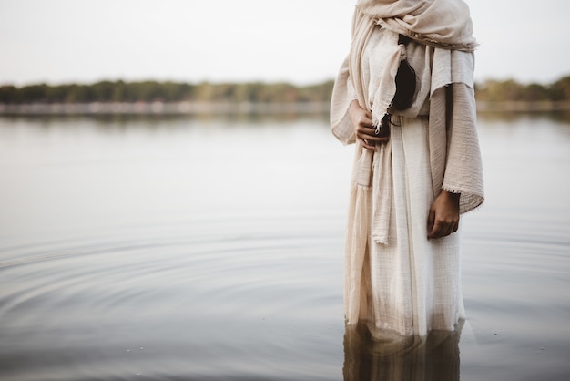 Belle photo d'une femme portant une robe biblique en se tenant debout dans l'eau