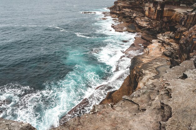 Belle photo d'une grande falaise à côté de l'eau bleue un jour sombre