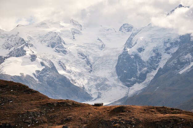 Belle photo d'une maison au bord de la falaise avec des montagnes enneigées