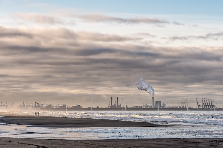 Photo gratuit belle photo d'une mer avec des moulins à vent et une usine au loin sous un ciel nuageux