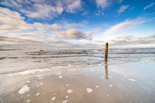 Belle photo de la mer qui monte vers le rivage sous un ciel bleu nuageux