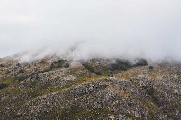 Belle photo d'une montagne couverte de nuages épais blancs