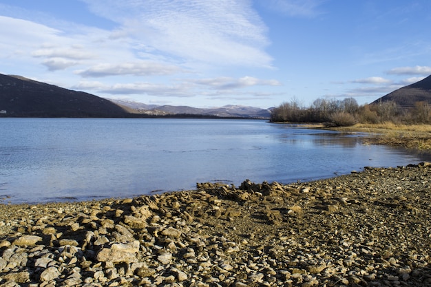 Belle photo panoramique d'un rivage serein pierreux sous un ciel bleu nuageux