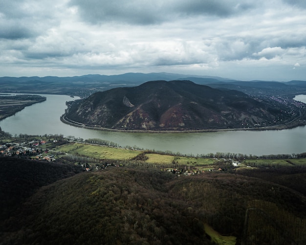 Belle photo d'une rivière entre les collines sous le ciel nuageux