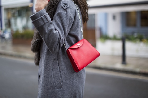 Photo gratuite belle photo d'un sac à main blanc porté par une dame sur un manteau sombre sur une route