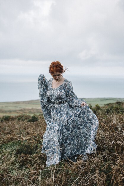 Belle photo verticale d'une femme au gingembre avec une peau d'un blanc pur dans une jolie robe bleue