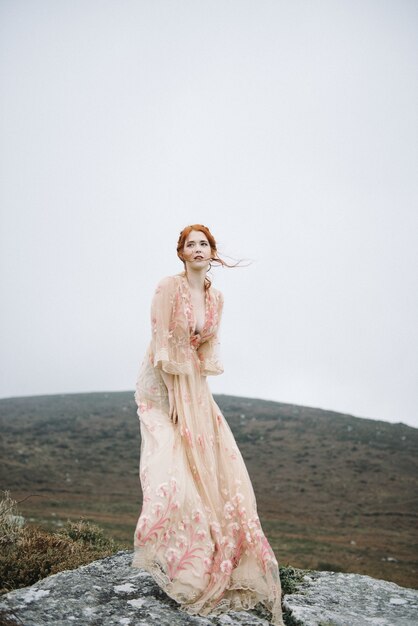 Belle photo verticale d'une femme au gingembre avec une peau d'un blanc pur dans une jolie robe rose