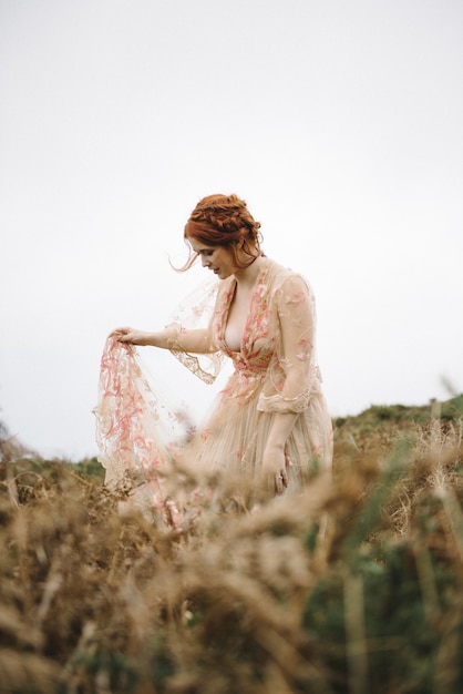 Belle photo verticale d'une femme au gingembre avec une peau d'un blanc pur dans une jolie robe rose