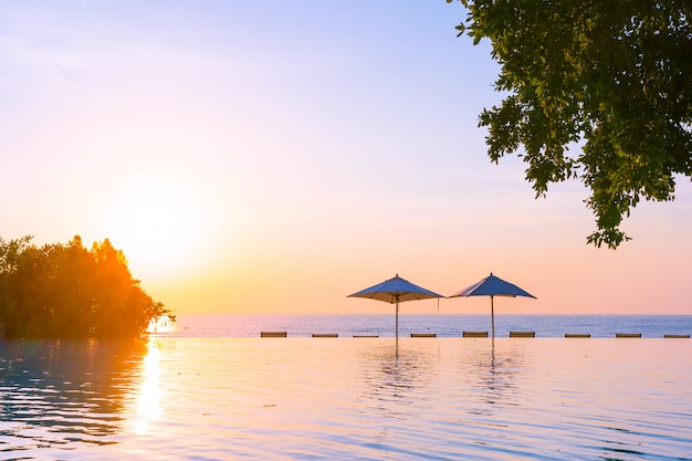 Photo gratuite belle piscine en plein air avec parasol et chaise longue dans le complexe hôtelier pour se détendre