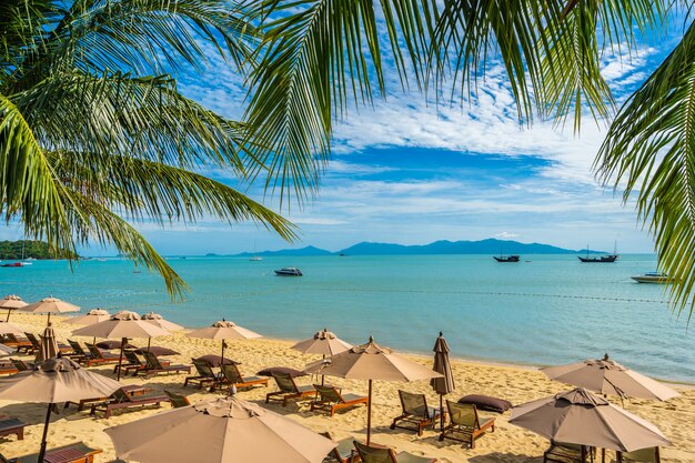 Belle plage tropicale mer et océan avec cocotier et parasol et chaise sur ciel bleu