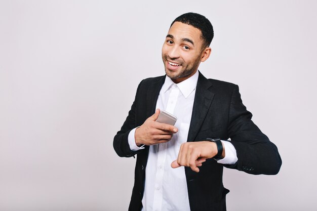 Belle réussite, bons résultats dans la carrière de beau jeune homme en chemise blanche, veste noire souriant avec téléphone. Homme d'affaires élégant, souriant.