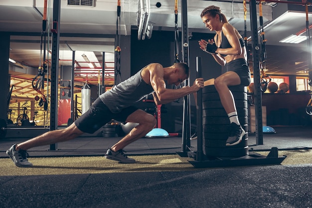 Belle séance d'entraînement de formation de jeune couple sportif dans la salle de sport ensemble