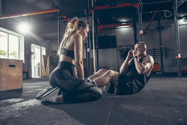 Belle séance d'entraînement de jeune couple sportif dans la salle de gym ensemble.