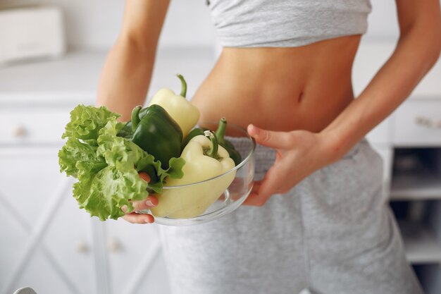 Belle et sportive femme dans une cuisine avec des légumes