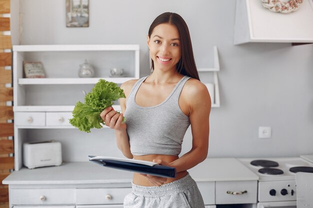 Belle et sportive femme dans une cuisine avec des légumes