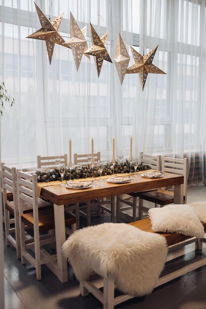 Belle table de service de Noël avec bougies et décoration de sapin en gros plan intérieur moderne et confortable. Célébration des vacances de décembre nouvel an entouré de verres et assiettes décorés de saison
