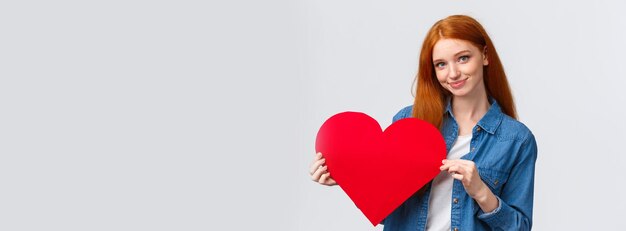 Belle et timide adolescente rousse mignonne avoue sa sympathie donner un cadeau le jour de la Saint-Valentin à la main