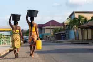 Photo gratuite belles femmes africaines allant chercher de l'eau à l'extérieur