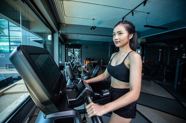 De belles femmes en forme physique se préparent à courir sur le tapis de course dans le gymnase.