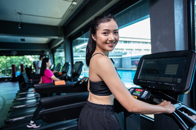 De belles femmes en forme physique se préparent à courir sur le tapis de course dans le gymnase.