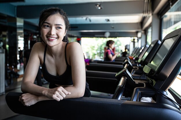 De belles femmes en forme physique se préparent à courir sur le tapis de course dans le gymnase.