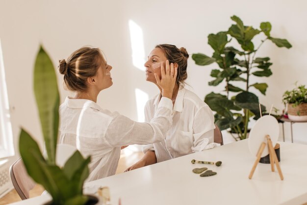 Les belles femmes à la peau claire utilisent une crème de jour hydratante pour les peaux sensibles dans une pièce claire. Soins personnels et journée de la santé, concept