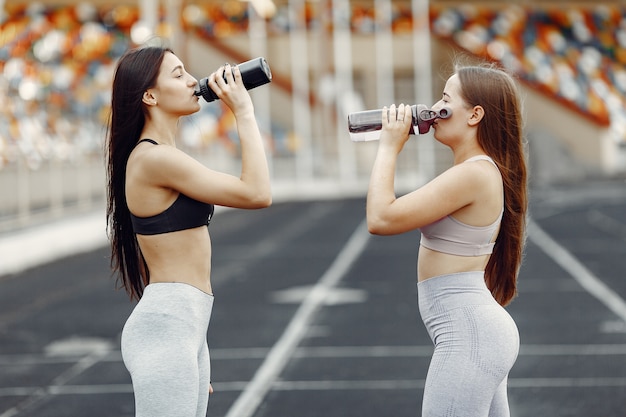 Belles filles au stade. Filles de sport dans un vêtement de sport. Les gens avec une bouteille d'eau.