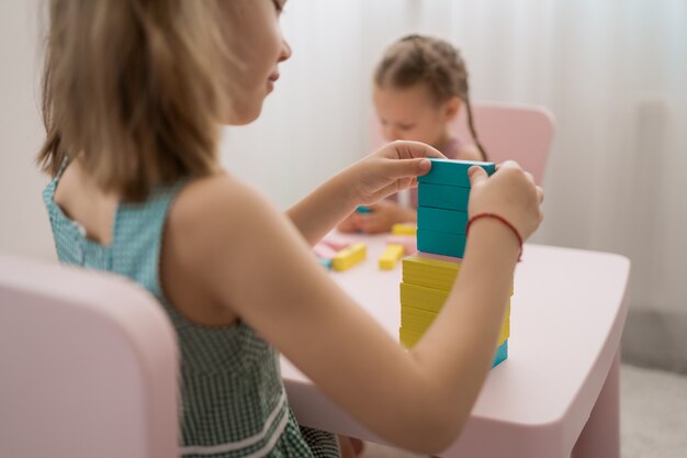 Belles filles caucasiennes jouant avec des blocs multicolores en bois