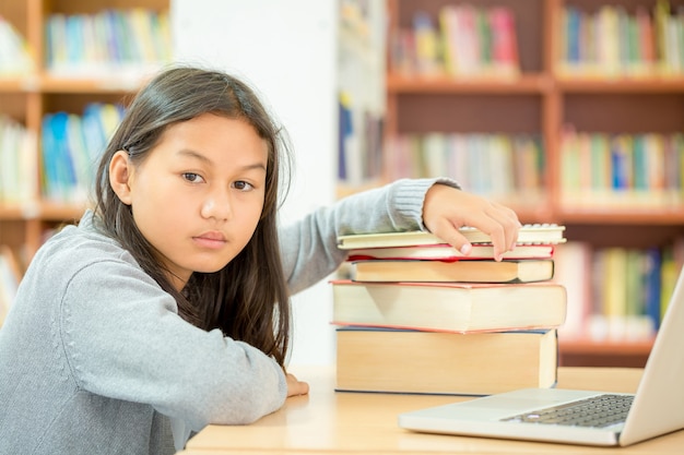 De belles filles lisent des livres dans des bibliothèques qui ont du mal à lire beaucoup de livres