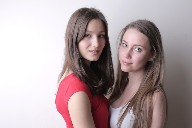 Belles jeunes femmes debout contre un mur blanc