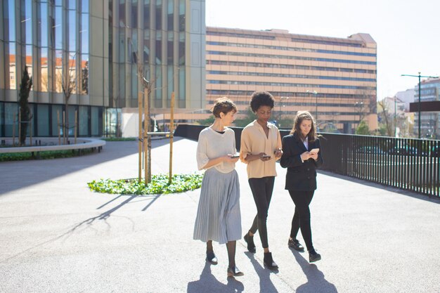 Belles jeunes femmes parlant en marchant dans la rue