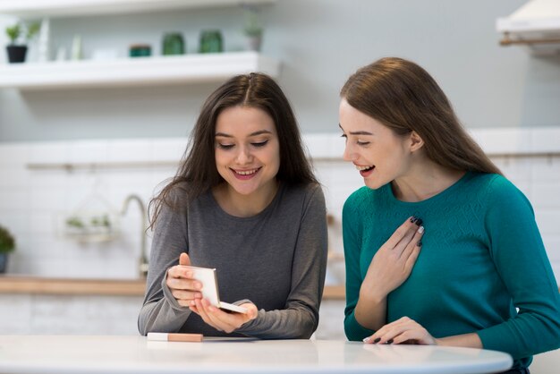 Belles jeunes femmes regardant des accessoires de maquillage