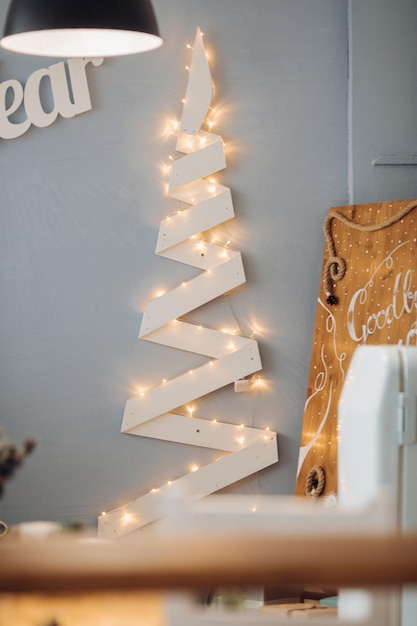 Belles lettres blanches Happy New Year au mur bleu dans un studio de décoration moderne. Intérieur de Noël confortable dans une salle de design confortable entourée de lumière d'une lampe vintage décorative