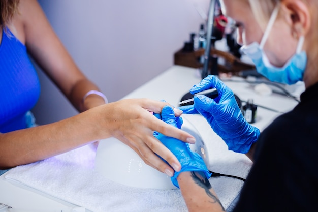 Belles mains féminines Traitement des ongles des doigts processus de fabrication Foreuse à ongles professionnelle en action Concept de soins de beauté et des mains