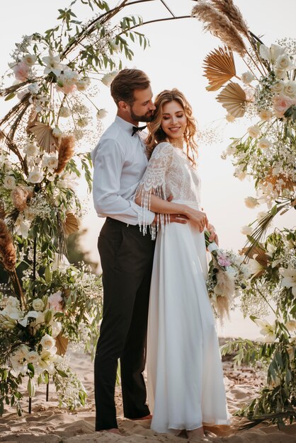 Belles mariées et mariés ayant un mariage sur la plage