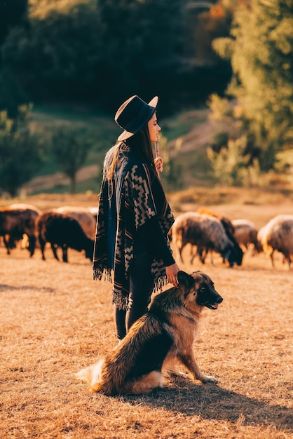 Photo gratuite berger femelle avec un chien broute un troupeau sur la pelouse