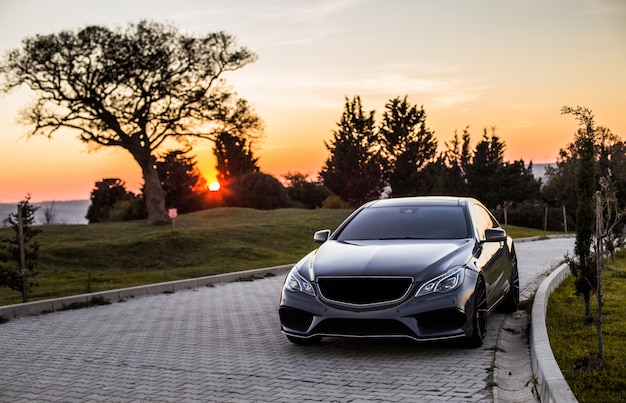 Une berline de luxe grise au coucher du soleil.