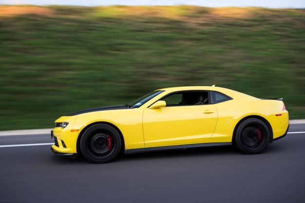 Berline sport jaune sur la route, vue de côté.