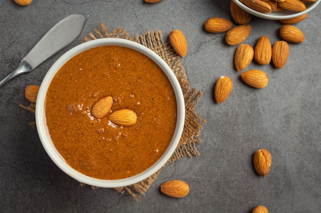 Beurre d'amandes biologiques crus sur fond sombre